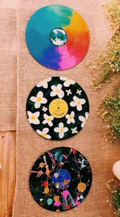 three different colored plates sitting next to each other on top of a wooden tablecloth