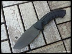 a large knife laying on top of a wooden floor next to a tile flooring