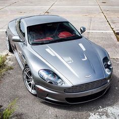 a silver sports car parked in a parking lot next to a curb with no cars on it