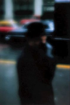 a blurry image of a man walking down the street with a cell phone in his hand