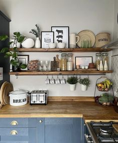 a kitchen with blue cabinets and shelves filled with items on top of the wooden counter