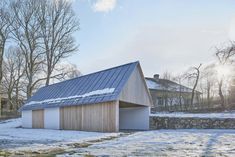 a house with a metal roof in the middle of snow covered ground next to trees