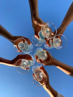 several people are holding wine glasses in the middle of a circle on a sunny day