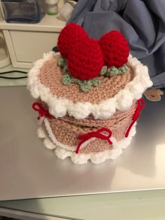 a crocheted cake with two strawberries on top