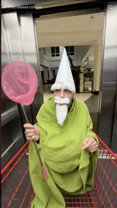 an old man in a green robe and white hat holding two pink lollipops