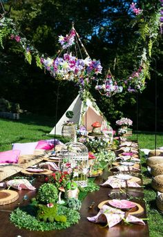 a long table with flowers and birdcage hanging from it's sides on the grass