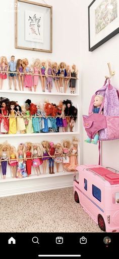 there are many barbie dolls on the shelves in this room, and one is holding a pink suitcase