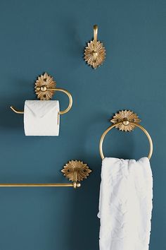 a bathroom with blue walls and gold fixtures on the towel rack, toilet paper roll and towels