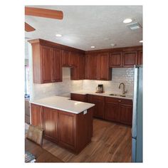 a kitchen with wooden cabinets and white counter tops