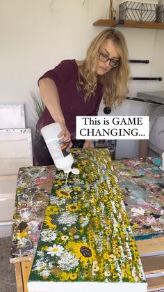 a woman is painting flowers on a table with a sign that says, this is game changing