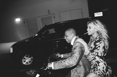 a man and woman riding on the back of a motorcycle in front of a car