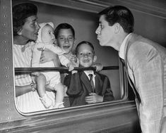 an old black and white photo of people looking at a baby in a train car