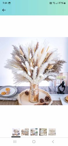 a vase filled with feathers sitting on top of a table next to plates and cups