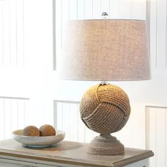 a table with a bowl and lamp on it in front of a white paneled wall