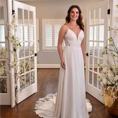 a woman in a white wedding dress standing on a wooden floor next to an open door