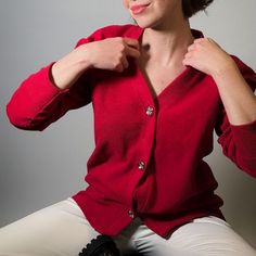 The Rosie cardigan in red is a vibrant and cozy garment that effortlessly combines comfort with style. This piece is  made of luxury cotton piqué imported from Italy. The rich red hue adds a pop of color, making it a versatile piece that can elevate both casual and semi-formal ensembles.  Adding a touch of elegance and sophistication, the cardigan features an embroidered logo on the back and under the collar, and includes silver buttons with shield motif that run down the front, providing a polished and timeless aesthetic.   Whether worn open or buttoned up, this cotton red cardigan is a versatile and stylish wardrobe staple.  93% Cotton, 7% Polyamide Wash Max 30º Do not use bleach Iron Max 150º Dry cleaning Do not use dryer Dry on horizontal surface Elegant Red V-neck Cardigan, Red Cotton V-neck Cardigan, Classic Red Cotton Cardigan, Elegant Red Cardigan For Fall, Classic Red Fitted Cardigan, Classic Fitted Red Cardigan, Classic Red Sweater For Fall, Elegant Red Winter Cardigan, Stylish Wardrobe