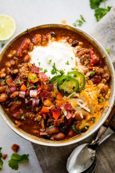 a bowl filled with chili, beans and sour cream