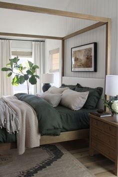 a bedroom with a four poster bed and green linens on the covers, along with a rug