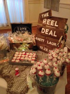 a table topped with lots of cupcakes next to a sign that says the reel deal