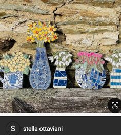 three vases with flowers are sitting on a ledge in front of a stone wall