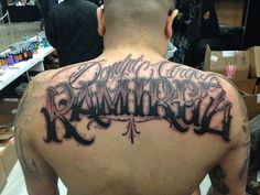 the back of a man's upper half covered in black and grey ink that reads,