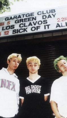 three young men are standing in front of a movie theater marquee with the words garage club los clavos and sick of it all