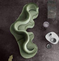 a green chair sitting on top of a floor next to a cup and saucer