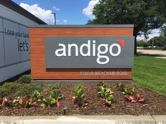 the sign for andigo is located in front of a building with landscaping around it