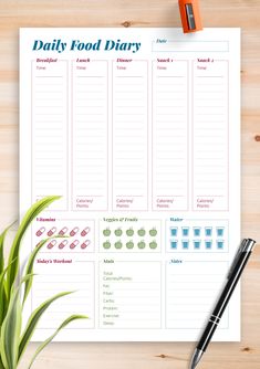 a printable daily food diary on a clipboard next to a pen and plant