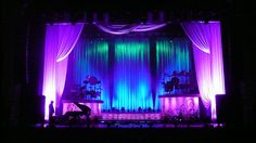 the stage is lit up with purple and green lights