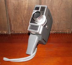 an old camera sitting on top of a wooden table