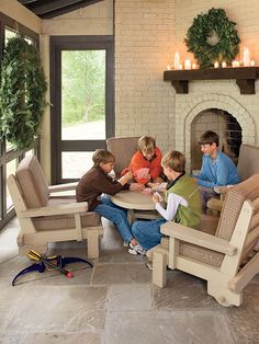 four people sitting around a table in front of a fireplace