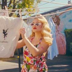 a woman holding up a white shirt on a clothes line