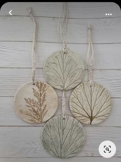 three ceramic tree ornaments hanging on a white wooden wall, with the words'home is where the trees are'written below them