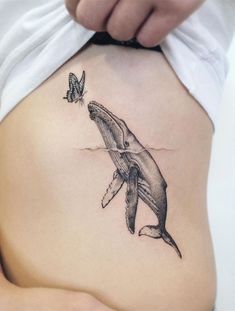 a woman's stomach with a shark tattoo on it and a butterfly flying by