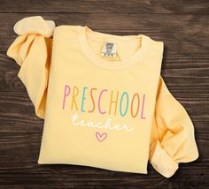 Preschool Teacher Sweatshirt, Comfort Colors, Back To School, Teacher appreciation, Prek Teacher Sweatshirt, Preschool Teacher Gift Luxurious comfort and style are what this unisex, garment-dyed sweatshirt is all about. It's made with 80% ring-spun cotton and 20% polyester and the fabric is 3-end garment-dyed, ring-spun, color-blast fleece with a 100% cotton face. Each sweatshirt comes with a relaxed fit, a rolled-forward shoulder, and a back neck patch.  .: 80% ring-spun cotton, 20% polyester . School Crew Neck Sweatshirt With Name Print, Cute Cotton Sweatshirt For School, Cute Long Sleeve College T-shirt, School Long Sleeve T-shirt With Name Print, Cute Letter Print Sweatshirt For School, Cute Long Sleeve T-shirt For School, Long Sleeve Cotton Top For School Events, Long Sleeve Cotton Tops For School, Cotton Long Sleeve Tops For School Events