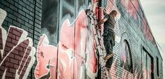 a man climbing up the side of a red and black train with graffiti on it