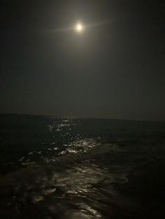 the moon is shining over the ocean at night