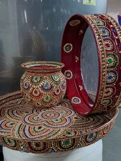 two vases sitting on top of a white pedestal covered in gold and red beads