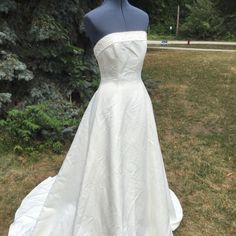 a white wedding dress on display in the grass