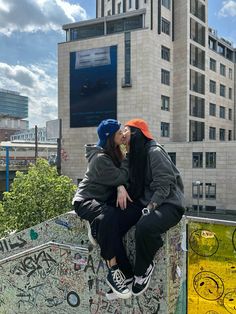 two people sitting on top of a skateboard ramp with graffiti all over the walls