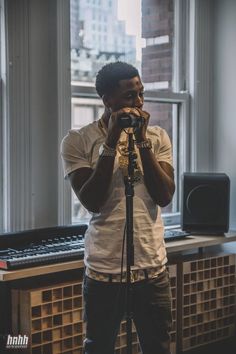 a man standing in front of a microphone with his hands to his face and looking at the camera