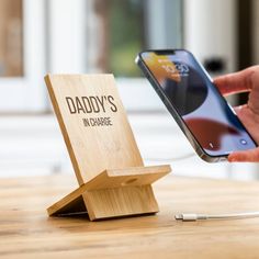 a person holding a cell phone next to a wooden stand that says daddy's in charge