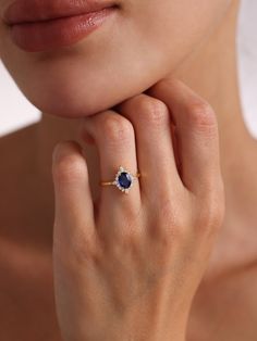 a close up of a person wearing a ring with a diamond and blue stone on it