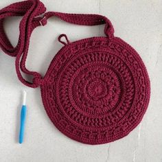 a crocheted bag with a blue handle on the floor next to a plastic toothbrush