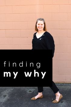 a woman standing in front of a brick wall holding a sign that says finding my why