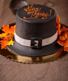 a black and white top hat with orange flowers on the rim, sitting on a wooden table