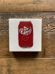 a red and white sticker with the word dr pepper on it sitting on top of a wooden surface