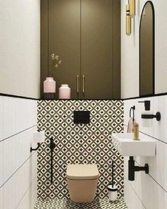 a white toilet sitting next to a sink in a bathroom with black and white tiles