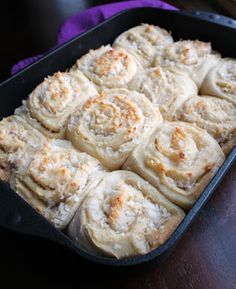 a pan filled with cinnamon rolls sitting on top of a wooden table